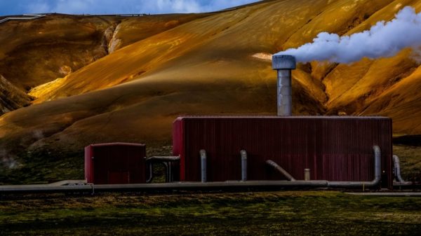 Central geotérmica roja emitiendo vapor sobre un dramático fondo montañoso amarillo-marrón. Francesco Ungaro / Pexels